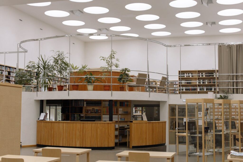 Spacious library interior with bookshelves, desks, and unique circular ceiling lights.